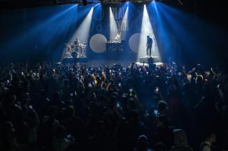 photo d'un concert de rock avec du public, les lumières sur la scène sont dans les teintes de bleu.