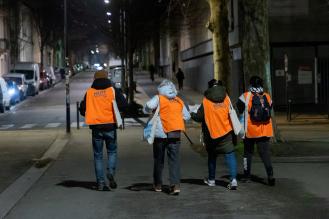 Photo de quatre bénévoles de la Nuit de la solidarité vues de dos, marchant dans la rue.