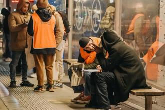 Photo de bénévoles de la Nuit de la solidarité discutant avec des personnes sans abri à un arrêt de bus.