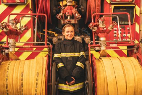 Anouk en uniforme de pompier se tient devant un camion de pompier