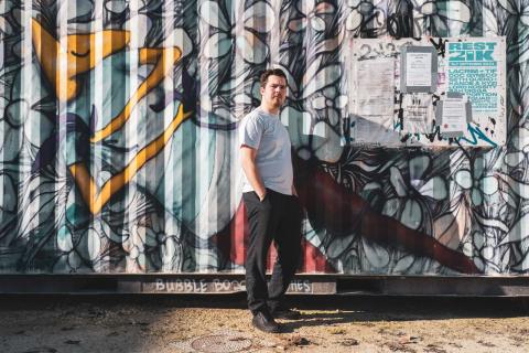 Timothée se tient devant une oeuvre de street-art peinte sur un container 
