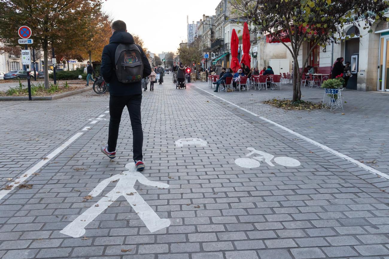 Photo d'une personne qui marchent sur une piste dédiée avec un logo piéton marqué au sol.