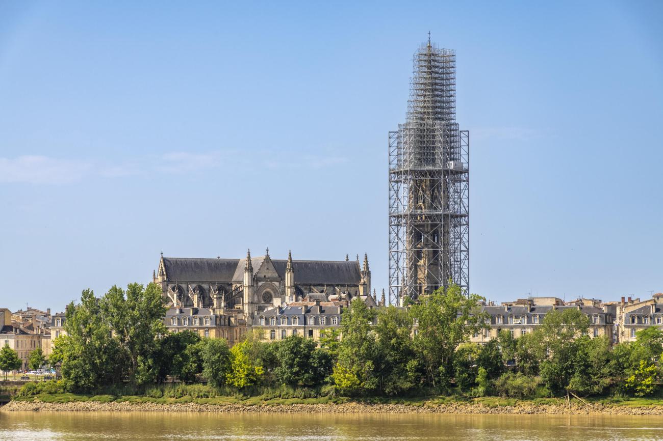 Photo de jour d'une vue depuis la Garonne de la flèche Saint-Michel, recouvert d'un échafaudage