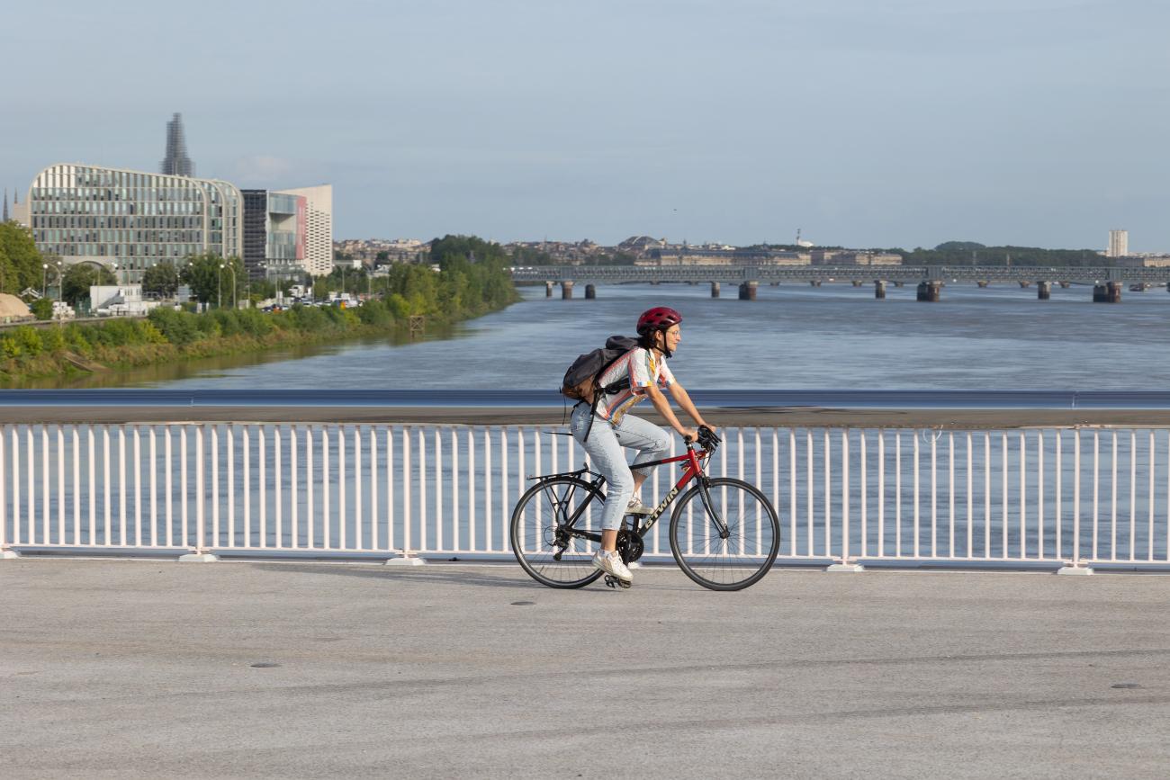 Photo d'une cycliste qui traverse à vélo le nouveau pont Simone Veil en direction de la rive droite.