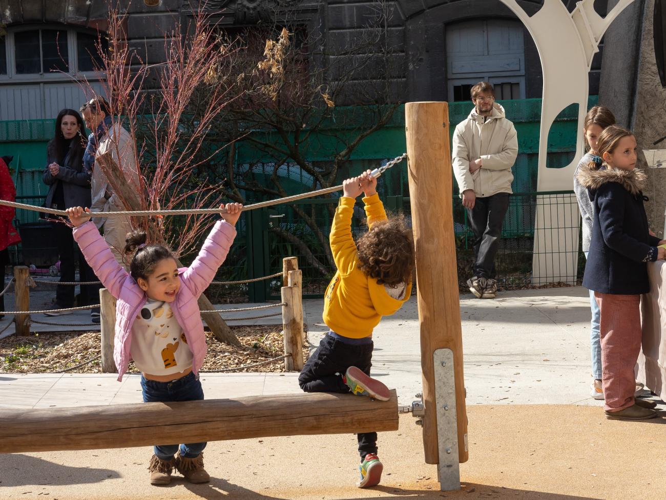 Des enfants qui jouent et des adultes qui discutent dans un cour d'école jouant, 
