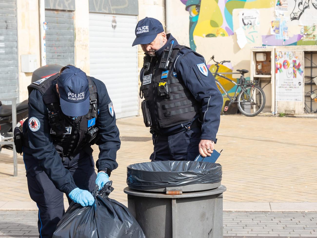 Deux agents de la Brigade anti-incivilités fouillent des poubelles