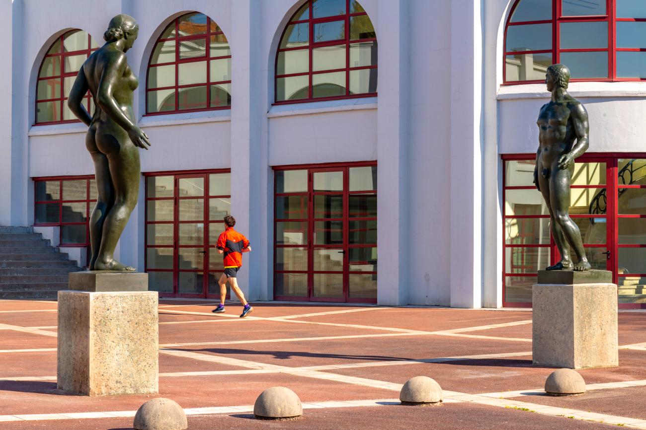 Un homme qui cours à côté des statues du parc Lescure