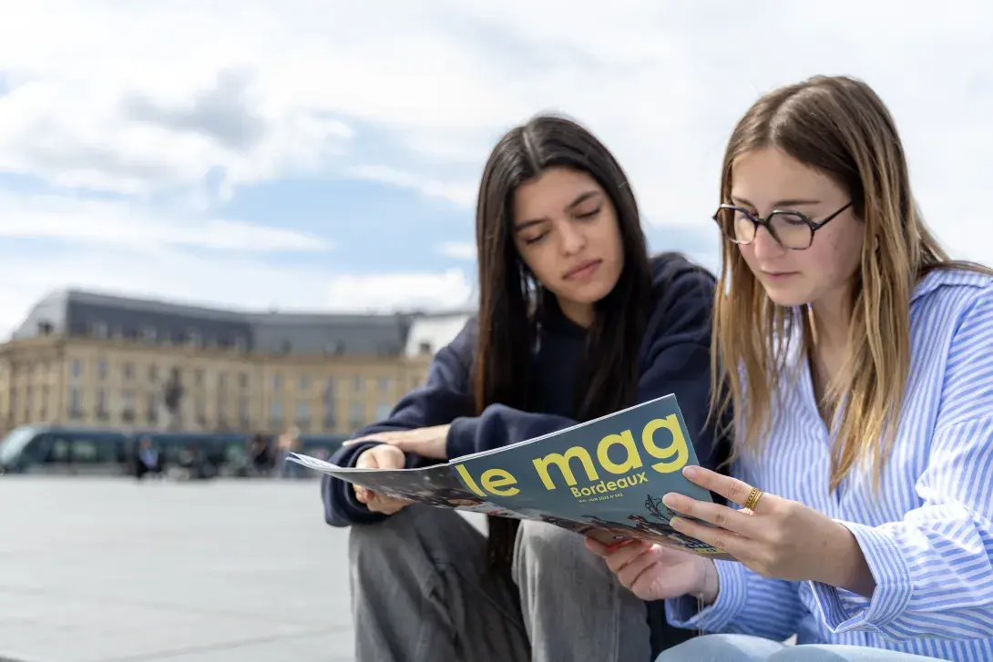 Deux jeunes femmes lisent le mag Bordeaux près de la place de la Bourse